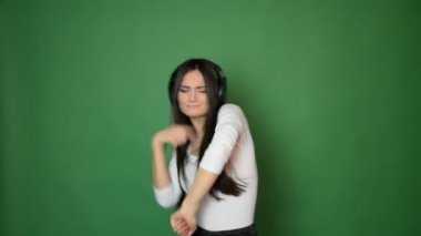 güzel çekici genç kız dans ve kulaklık müzik ile şarkı ve iyi konsept yeşil stüdyo arka planda izole hissediyorum