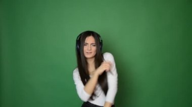 güzel çekici genç kız dans ve kulaklık müzik ile şarkı ve iyi konsept yeşil stüdyo arka planda izole hissediyorum