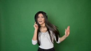 güzel çekici genç kız dans ve kulaklık müzik ile şarkı ve iyi konsept yeşil stüdyo arka planda izole hissediyorum