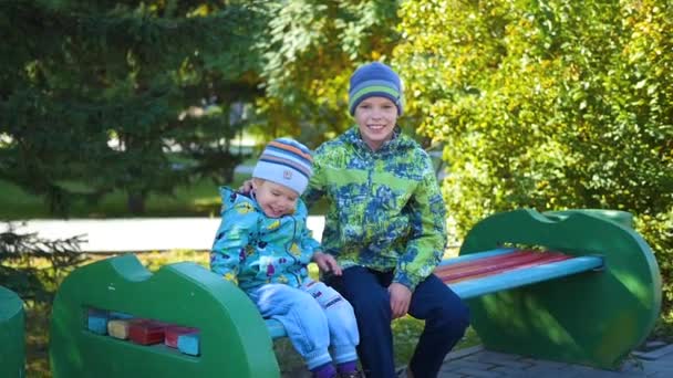 Děti bavit, hrát na lavičce v parku — Stock video