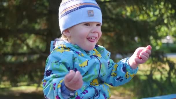 Μωρό που γελάει μέσα από το πάρκο κάθεται στον πάγκο — Αρχείο Βίντεο