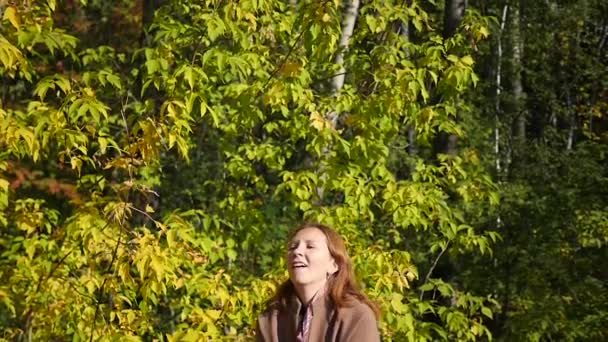 Дівчина кидає листя над головою в парку — стокове відео
