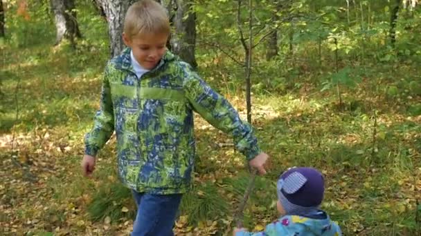 A criança brinca com seu irmão mais novo no Parque — Vídeo de Stock