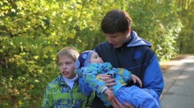 Genç aile Park'ta yürüyordunuz baba onun kollarında taşıyan oğlu