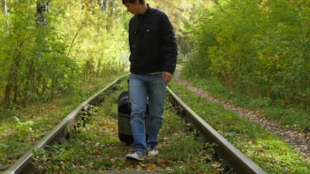 Guy with suitcase walking along railroad — Stock Video