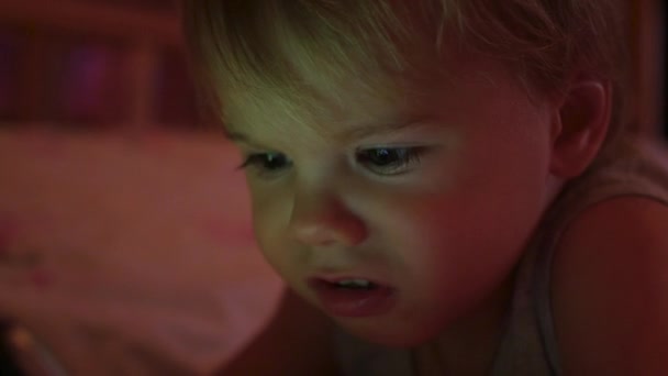 Un niño pequeño mira dibujos animados en la tableta tarde en la cara de primer plano de la noche — Vídeo de stock