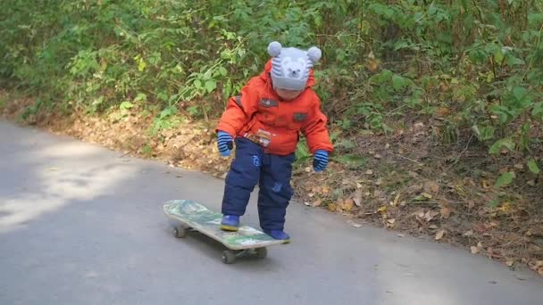 Küçük bir çocuk parkta bir kaykay binmek öğrenir — Stok video