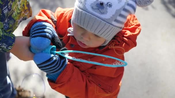 Ένα χαρούμενο παιδί μικρό φυσώντας φυσαλίδες σαπουνιού στο πάρκο — Αρχείο Βίντεο