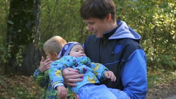 Junge Familie spaziert durch den Park, Vater trägt Sohn auf dem Arm — Stockvideo