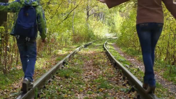 La ragazza e il bambino vanno senza sforzo sulla ferrovia dei binari — Video Stock