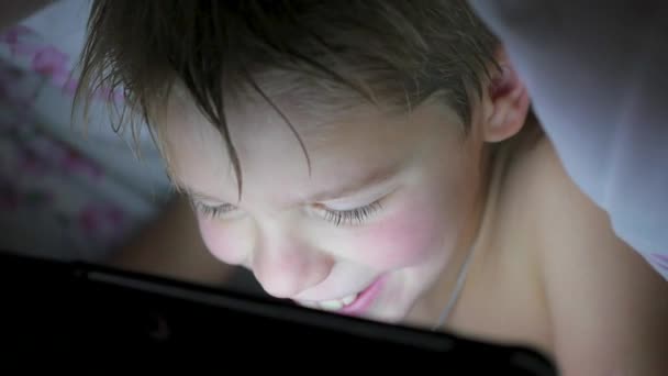 Chłopiec leży pod koc i oglądać bajki na touch pad — Wideo stockowe