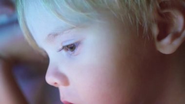 Oğlum battaniyenin altında yalan ve çizgi film izlerken pad closeup yüz touch