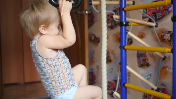 Un niño pequeño se dedica a los anillos de gimnasia en interiores — Vídeos de Stock