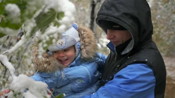 Хлопець і дитина грають зі сніжною гілкою дерева — стокове відео