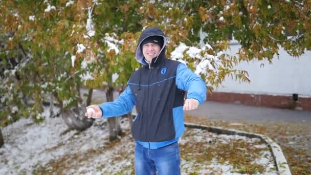 Хлопець кидає сніжку в осінній парк — стокове відео