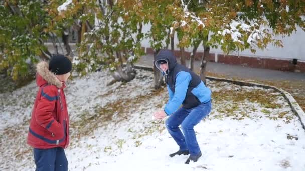 Kille kastar en snöboll i parken hösten — Stockvideo
