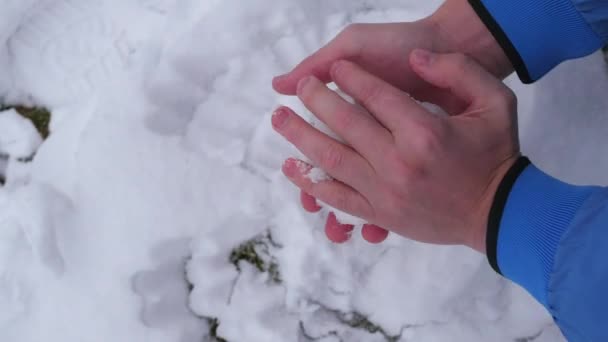 Kind beeldhouwt een sneeuwbal blote handen — Stockvideo