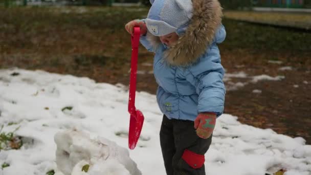 Niño jugando con la pala de nieve en el parque — Vídeos de Stock