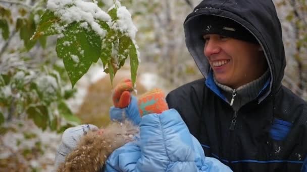 Cara e criança brinca com um ramo de árvore nevada — Vídeo de Stock