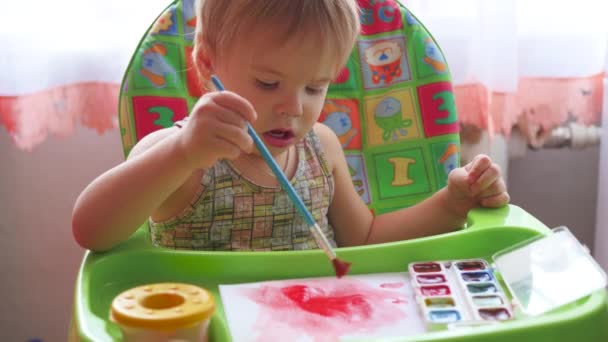 Little child draws paints on a sheet of paper — Stock Video