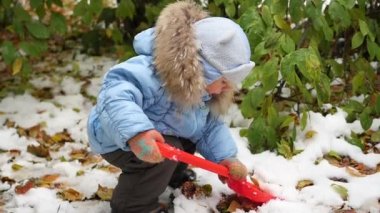 parkta kar küreği ile oynayan çocuk