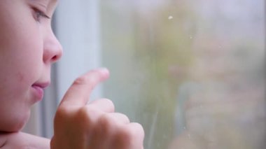 Çocuk bir parmak pencere camına çizer. Dışında bulanıklık kar
