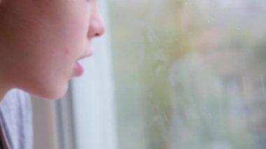 Çocuk bir parmak pencere camına çizer. Dışında bulanıklık kar