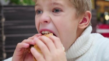 Çocuk bir fast food restoran tatlı bir sandviçi yiyor