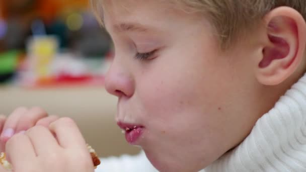Ребенок ест сэндвич в ресторане быстрого питания крупным планом — стоковое видео