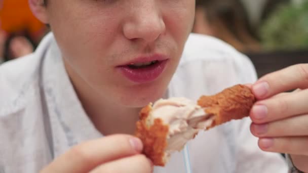 Chico come pollo frito en un restaurante de comida rápida primer plano — Vídeos de Stock