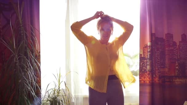 Chica divirtiéndose bailando en la ventana en la luz del sol — Vídeos de Stock