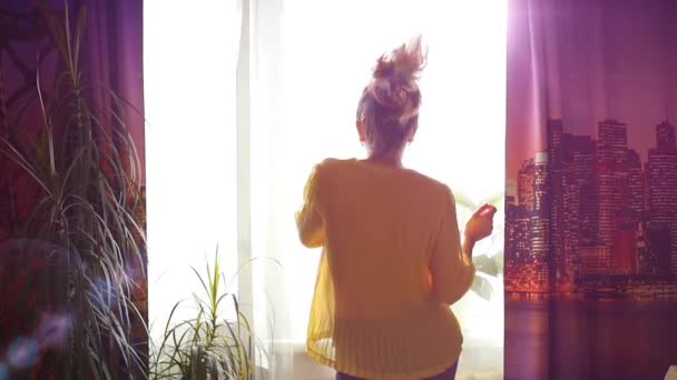 Дівчина весело танцює біля вікна на сонячному світлі — стокове відео