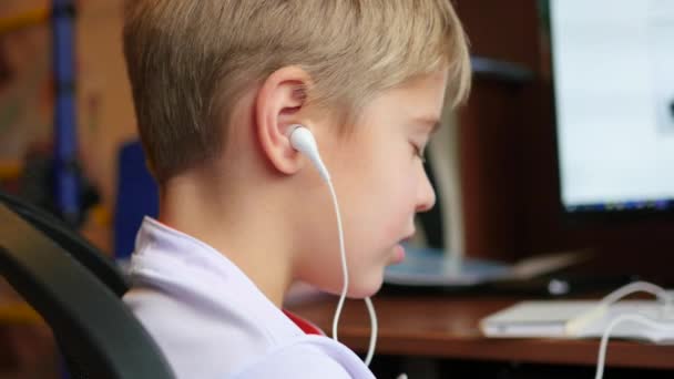 El niño escucha música en el teléfono inteligente en los auriculares en casa — Vídeos de Stock