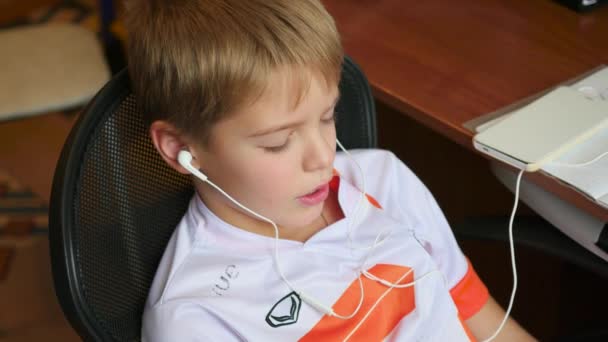 Ребенок слушает музыку на смартфоне в наушниках дома — стоковое видео