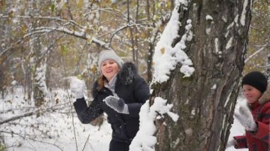 Kış parkta ağaç arkasından aile atarak oynarken snowballs