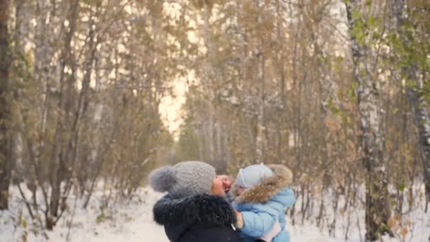 Mutter spielt mit Baby im Winterpark. Mutter wirft das Kind hin — Stockvideo