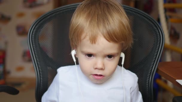 A criança escuta música no smartphone nos fones de ouvido em casa — Vídeo de Stock