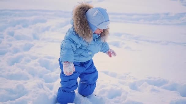 El niño camina en la nieve profunda deriva en el parque — Vídeo de stock