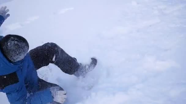 Niño rueda la cabeza sobre los talones con la colina en la nieve — Vídeo de stock