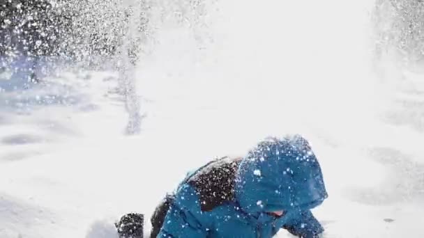 Kind überschüttet sich mit Schnee und lächelt ihn im Winterpark — Stockvideo