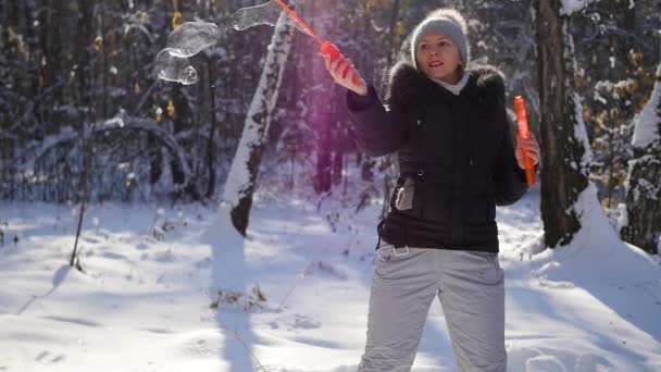 Fata face bule mari de săpun cu încântare în parc de iarnă într-o zi însorită — Videoclip de stoc