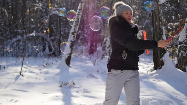 Chica hace grandes burbujas de jabón con deleite en invierno Parque en un día soleado — Vídeo de stock