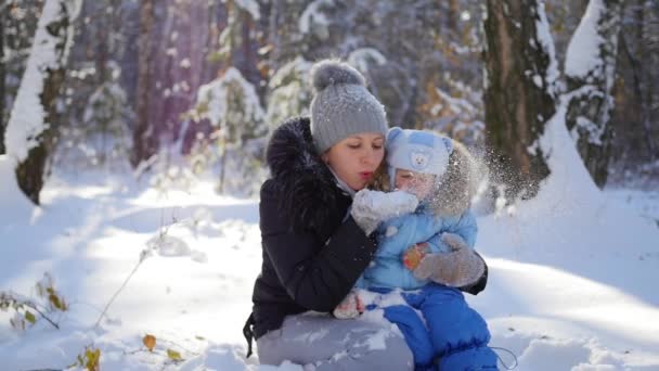 Девушка с ребенком играет со снегом в парке в солнечный день — стоковое видео