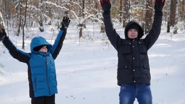 Un ragazzo con un bambino cadere nella neve e fare un angelo di neve al rallentatore — Video Stock