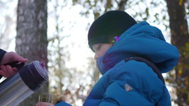 Çocuk Kışın açık bir kupa sıcak çay içiyor. Güneşli gün