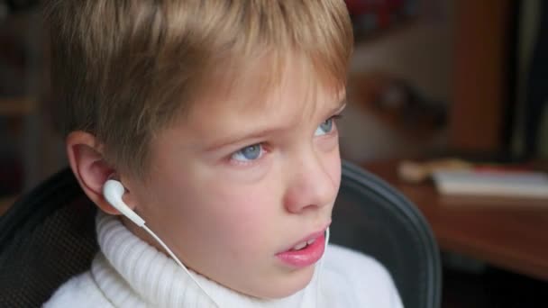 Barnet lyssnar på musik på smartphone i hörlurarna och humle huvud i hem — Stockvideo
