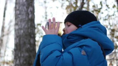 Çocuk Kışın açık bir kupa sıcak çay içiyor. Güneşli gün