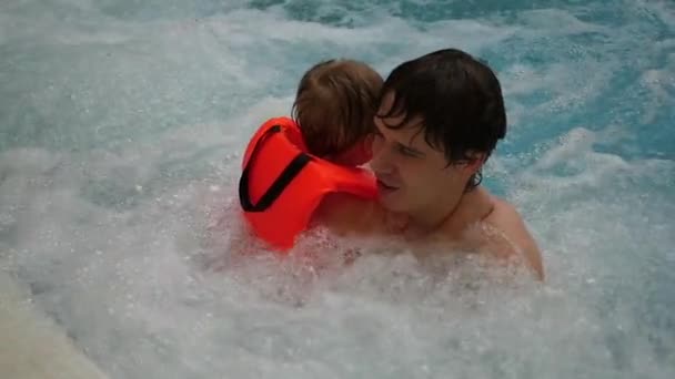 Hombre baña al bebé feliz en el baño con un jacuzzi — Vídeos de Stock
