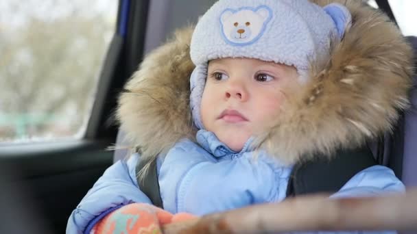 El niño monta en el coche en el asiento trasero y mirando por la ventana — Vídeos de Stock