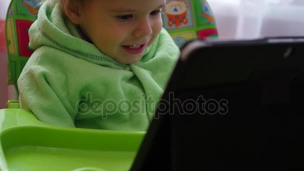 Щаслива дитина дивиться мультфільми на планшеті і посміхається — стокове відео